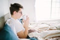 Man in bed drinking morning coffee in sunrise light. Royalty Free Stock Photo