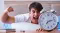 Man in bed frustrated suffering from insomnia with an alarm cloc