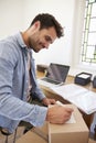 Man In Bedroom Running Business From Home Labeling Goods