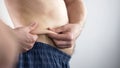 Man with beer belly looking at his folds, considering about dieting, body care Royalty Free Stock Photo