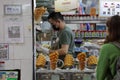 Man behind a counter preparing fresh waffles in a bustling street in China