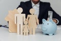 Man behind of figures of young family and piggy bank with cash, purchase or mortgage concept