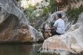 Man from behind meditating on top of a rock at the foot of a mountain river Royalty Free Stock Photo