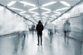 Man from behind standing at busy walkway with people in motion blur