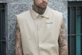 Man with beige Maison La Ponte shirt and tattoes before Emporio Armani fashion show, Milan Fashion