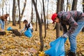 Man bending over, picking up trash in a seasonal forest at autumn