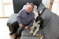 A man bent his ear to Husky& x27;s face on the sofa Royalty Free Stock Photo