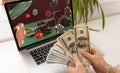 Man betting on sports using laptop at table, closeup. Bookmaker website on screen Royalty Free Stock Photo