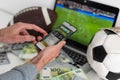 Man betting on sports using smartphone and laptop at table, closeup. Bookmaker websites on displays Royalty Free Stock Photo