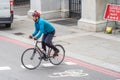 A man on a bicycle crosses the street at a pedestrian crossing against a background sign keep the distance. UK, London