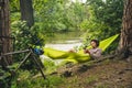 Man on bicycle trip at camping by lake is relaxing in green hammock while listening to music. Active recreation theme in Royalty Free Stock Photo