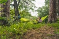 Man on bicycle trip at camping by lake is relaxing in green hammock while listening to music. Active recreation theme in Royalty Free Stock Photo