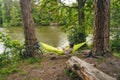 Man on bicycle trip at camping by lake is relaxing in green hammock while listening to music. Active recreation theme in Royalty Free Stock Photo