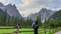 A man with a big hiking backpack enjoying the distant view on Italian Dolomites. There is a lush green meadow Royalty Free Stock Photo