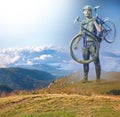 The man with bike in sand standing on mountains background. Collage Royalty Free Stock Photo