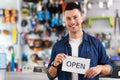 Man in bike shop holding open sign