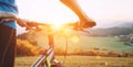 Man with bike stay on the top of hill and enjoying the sunset. Man hands on the bike steering wheel close up image