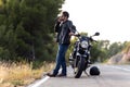 Man biker talking on the phone to the insurance of his motorcycle after having suffered a breakdown on the road