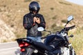 Man biker talking on the phone to the insurance of his motorcycle after having suffered a breakdown on the road