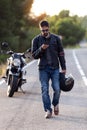 Man biker walking on the road while using her mobile phone after having suffered a breakdown on the road Royalty Free Stock Photo