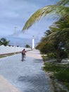 Man biking along the pathway towards lighthouse in tropics