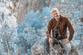 A man with binoculars is resting, sitting on a rock in the Ural mountains Royalty Free Stock Photo