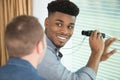 man with binoculars at window turning to talk to friend