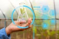 Man biologist pouring liquid from test tube in greenhouse.