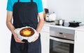 Man in black apron showing a cheesecake. Kitchen concept Royalty Free Stock Photo