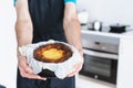 Man in black apron showing a cheesecake. Kitchen concept Royalty Free Stock Photo