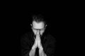 A man on a black background. Hands are folded in the position of prayer.Inner silence. Royalty Free Stock Photo
