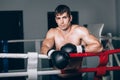 Man in black boxing gloves on the ropes of the ring is worth. Recreation. Portrait strong-willed person. Royalty Free Stock Photo