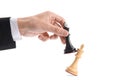Man with black chess king knocking over white one on white background, closeup. Competition concept Royalty Free Stock Photo