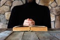 A man in black clothes in front of an open old book the Bible or the Koran, the concept of prayer, study, witchcraft Royalty Free Stock Photo