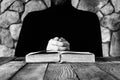 A man in black clothes in front of an open old book the Bible or the Koran, the concept of prayer, study, witchcraft. Royalty Free Stock Photo