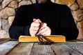 Man in black clothes with a rosary in his hands in front of an open old book bible or quran Royalty Free Stock Photo