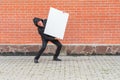 Man with blank white canvas stands against red brick wall background Royalty Free Stock Photo