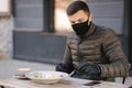 Man in black face mask sitting in cafe and prepared for eating vegan salad. Quarantine cafe concept. Covid-19 Royalty Free Stock Photo