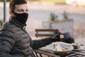 Man in black face mask sitting in cafe and prepared for eating vegan salad. Quarantine cafe concept. Covid-19 Royalty Free Stock Photo