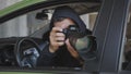 A private detective or photojournalist secretly takes photos from a car window with a long-focus lens. Royalty Free Stock Photo