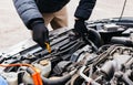 Man in black gloves checking the oil level in a car outdoors in winter. Car mechanic engineer working in car repair service. Male Royalty Free Stock Photo