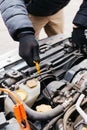 Man in black gloves checking the oil level in a car outdoors in winter. Car mechanic engineer working in car repair service. Male Royalty Free Stock Photo