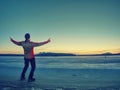 Man in black gray jacket on ice looking over frozen lake