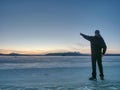 Man in black gray jacket on ice looking over frozen lake