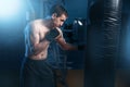 Man in black handwraps exercises with bag in gym