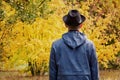 Man in a black hat is standing in the forest. Autumn concept. Back view Royalty Free Stock Photo