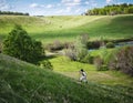 Man in black hat with a stic climbs the slope on a hill