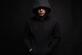 Man in Black Hood in dark studio. Boy in a hooded sweatshirt Royalty Free Stock Photo