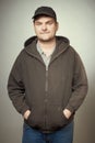 Rowdy bad man in black hooded shirt and black hat posing in studio