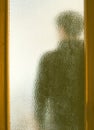 Man in black behind closed door through glass